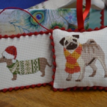 A Christmas dachshund and a cute pug in cross-stitch